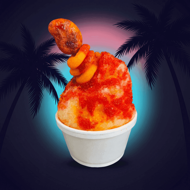 Mango Tango from Zogi's Shaved Ice & Lemonade — Red-orange mango shaved ice with crystalline candy sprinkles and an orange candy stack